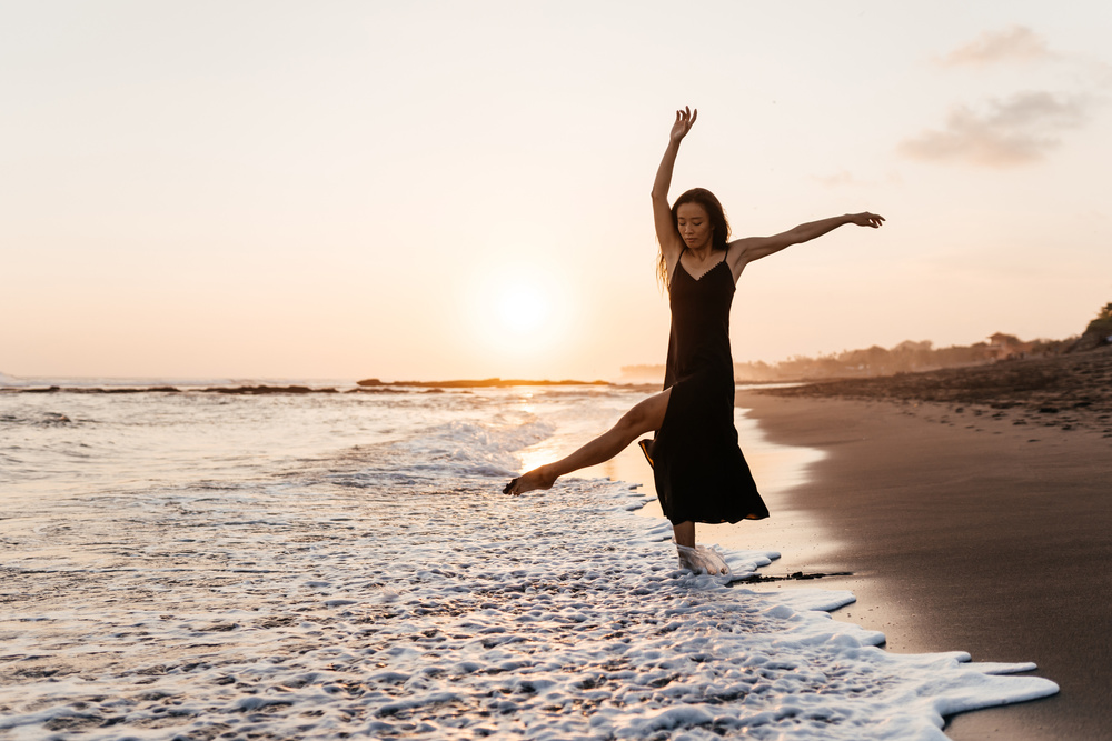 Freedom Chinese woman feeling free dancing at beach sunset.
